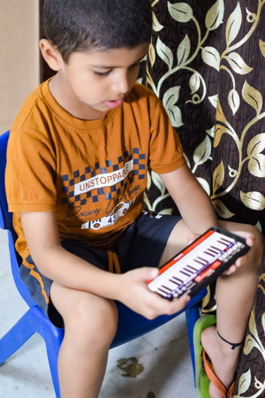 Portrait of Asian smart happy little boy using Mobile phone at home. Little boy holding mobile smart phone, online back to school concept. Online Class conceptの写真素材