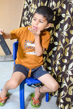 Portrait of Asian smart happy little boy using Mobile phone at home. Little boy holding mobile smart phone, online back to school concept. Online Class conceptの写真素材