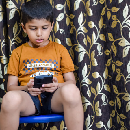 Portrait of Asian smart happy little boy using Mobile phone at home. Little boy holding mobile smart phone, online back to school concept. Online Class conceptの写真素材