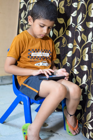 Portrait of Asian smart happy little boy using Mobile phone at home. Little boy holding mobile smart phone, online back to school concept. Online Class conceptの写真素材