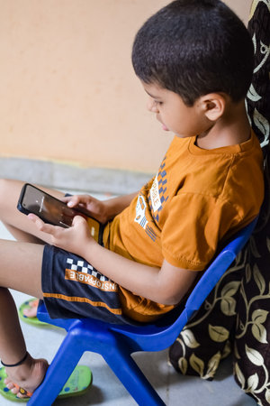 Portrait of Asian smart happy little boy using Mobile phone at home. Little boy holding mobile smart phone, online back to school concept. Online Class conceptの写真素材