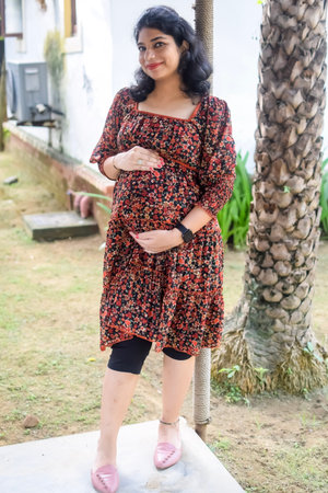 A pregnant Indian lady poses for outdoor pregnancy shoot and hands on belly, Indian pregnant woman...