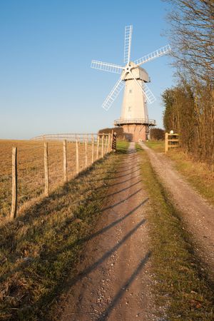 Old windmill with path and fence against clear blue skyの写真素材