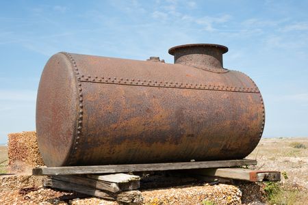 Close up detail of old rusty fuel tank on wood planks against blue skyの写真素材