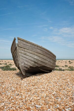 Abandoned shipwreck of wood fishing boat on beach against blue skyの写真素材