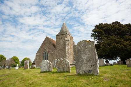 Old St. Clement's church and graveyard against blue sky with white clouds, Old Romney, Kent, UKの写真素材
