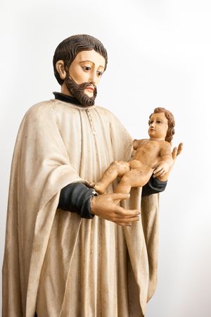 Old wood figurine of St Caetano holding baby Jesusの写真素材