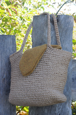 A handmade bag made of natural burlap hangs on a wooden fence.の写真素材