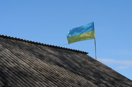 Flag of Ukraine on the roof of the house against the blue sky.の写真素材