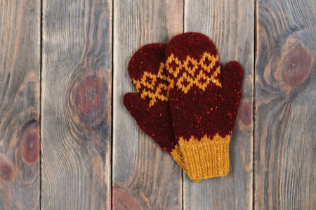 Knitted woolen mittens on a wooden background. Warm handmade things.