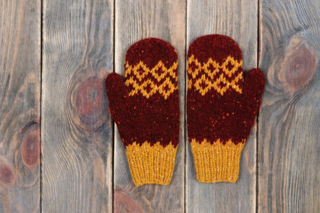 Knitted mittens on wooden background, top view. Winter clothes