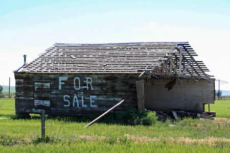 Crumbling building for sale propped up in a country fieldのeditorial素材