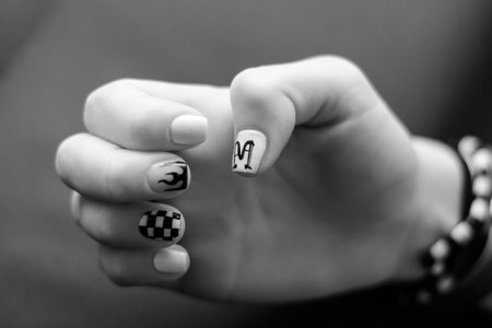 fingernails painted with different designs, letter M, flares and black and white checkered grids, black and white photoの写真素材