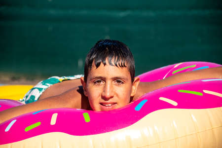 pretty child in pool on top of float relaxed and wet looking straight aheadの写真素材