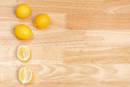 whole lemons and sliced lemons on wooden table, wooden bottom