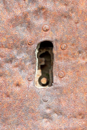 detail of an antique keyhole in a door veneered with nailed iron plateの写真素材