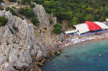 the Crimea. Simeiz. People relax during the summer holidays on the rocky coast of the Black sea. Vacationers swim, sunbathe, fish, climb on the rocks. The view from the top.のeditorial素材