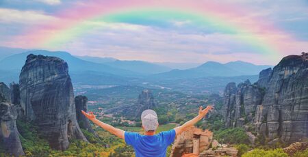 Man traveler praying at sunset mountain summit enjoying aerial epic rainbow view raised hands Travel lifestyle success relaxation. Emotional vacations, outdoor adventure freedom harmony nature conceptの写真素材