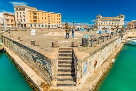 Syracuse - April 2019, Italy: Two tourists stand in front of The Archimedes Statue near Umbertino Bridge, which connects Syracuse and Ortygiaのeditorial素材