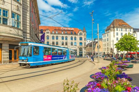 Oslo - June 2019, Norway: View of a street with a blue tram, old historical buildings and beautiful flowerbeds in the center of Osloのeditorial素材