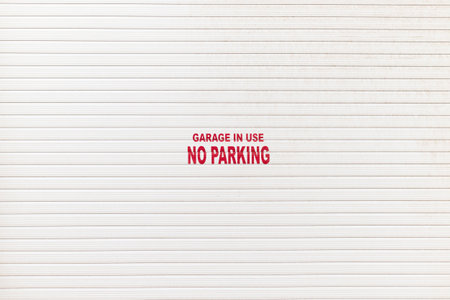 White garage door with a notice - garage in use no parkingの写真素材
