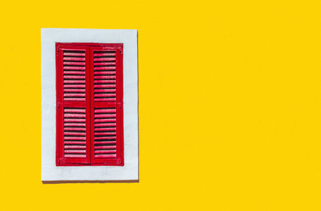 Minimalist style photo of yellow wall with red window in white frameの写真素材