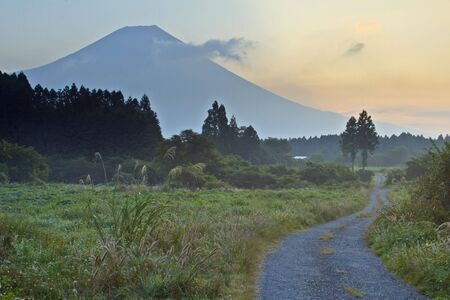 A rural country road with mount Fuji looming in the backgroundの写真素材