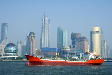 A bright red ship with the Shanghai skyline in the background