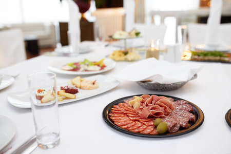 Food tray with delicious salami, pieces of sliced ham, sausage, tomatoes, salad and vegetable - Meat platter with selection - Cutting sausage and cured meat on a celebratory table.の写真素材