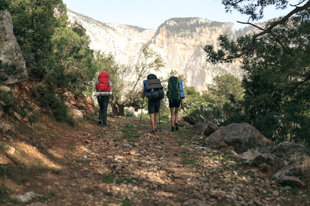 three hikers on trail in mountainsの写真素材