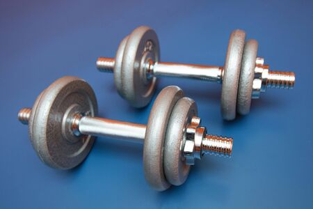 Two sports dumbbells on a blue backgroundの写真素材