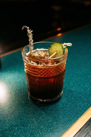 Alcoholic  summer Cocktail. Alcoholic beverage based on table with ice cubes and oranges.