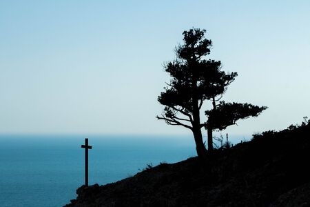 Silhouette cross on mountain sunsetの写真素材