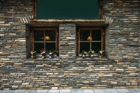 two windows with flowers on a stone wall background, texture backgroundの写真素材