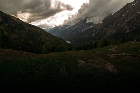 mountain landscape with a view of the forest and river in the mountains of Italy against the background of large cloudsの写真素材