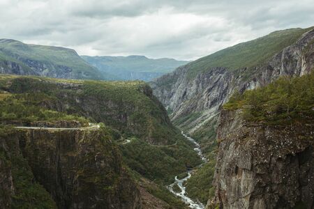 mountain landscape of norway with a waterfall on a background of cloudy skyの写真素材
