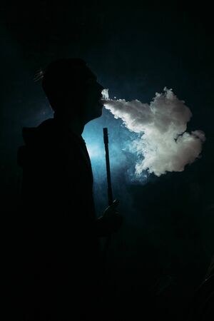 silhouette of a man inhaling smoke from a hookah, backgroundの写真素材