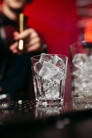 glass filled with ice on the background of the bartender and the red wallの写真素材