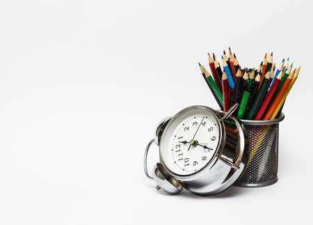 Alarm clock, colored pencils in a metal glass. The concept of time, and the business concept.の写真素材