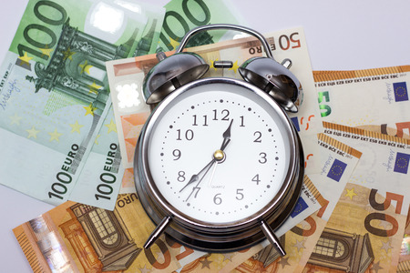 An alarm clock, and European paper money, on a white background. Business concept, time is money.の写真素材