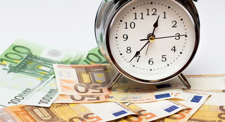 An alarm clock, and European paper money, on a white background. Business concept, time is money.の写真素材