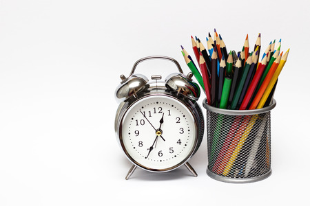 Alarm clock, colored pencils in a metal glass. The concept of time, and the business concept.の写真素材