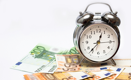 An alarm clock, and European paper money, on a white background. Business concept, time is money.の写真素材