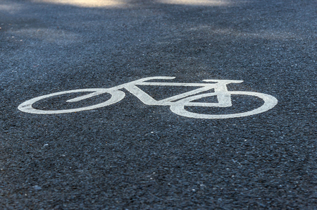 Close up view of a cyclist painted in white on an asphalt cycle track. Traffic sign to indicate a bike path in a town.の写真素材