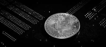 Gold and silver bitcoin on a dark background, on a printed circuit board. Cryptocurrency mining....