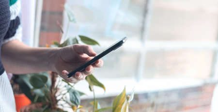 Woman holding smartphone, against the background of the room.