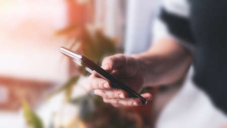 Woman holding smartphone, against the background of the room.の写真素材