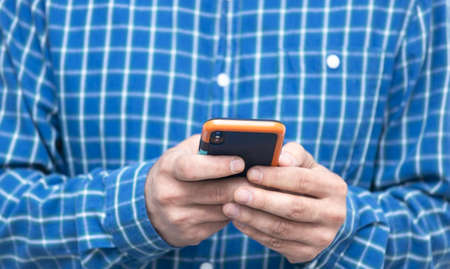 Hands of man typing text on mobile smartphone. Online chat chatting on application communication digital media website and social network.の写真素材