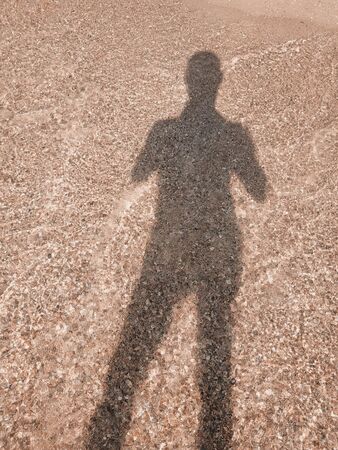 A man stands by the sea, his feet washed by the waves. Top down view.の写真素材