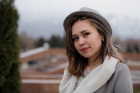 Winter closeup portrait of a cute lady in grey coat and scarf strolling in the parkの写真素材